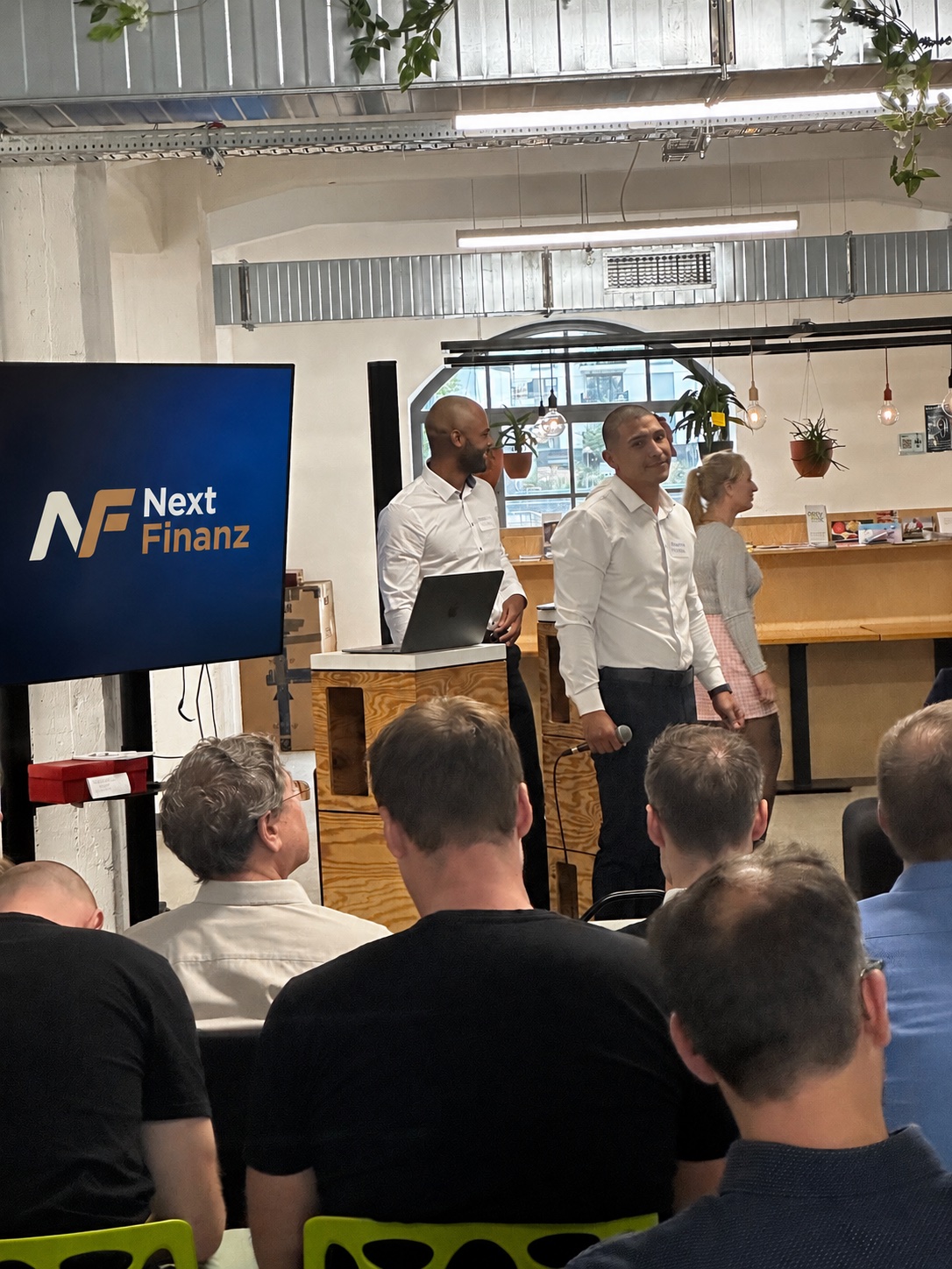 Next-Finanz-Vortrag vor Partnern, mit Next-Finanz-Logo auf dem Bildschirm